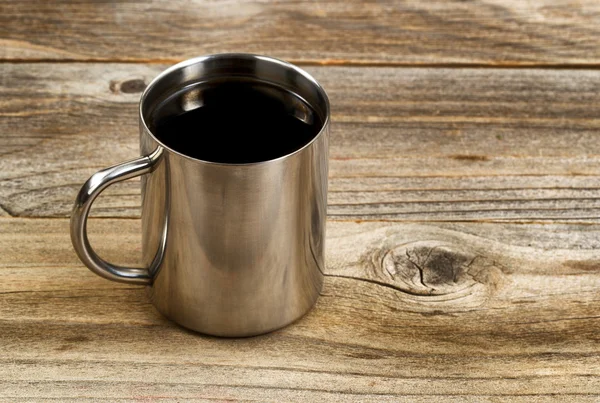 Fresh dark coffee in stainless steel cup on rustic wood — Stock Photo, Image