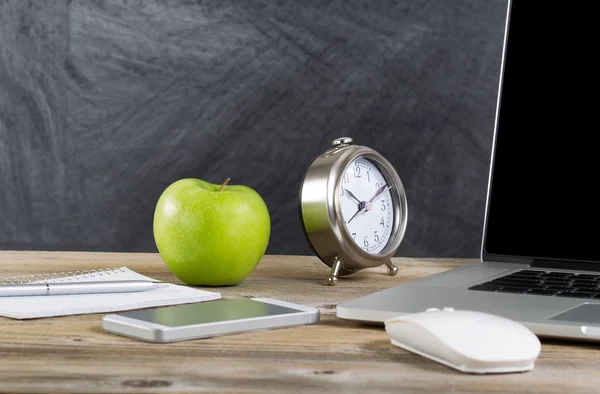 Old wooden desktop with technology and green apple