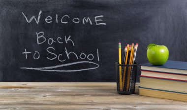 Eski ahşap masaüstü ile basit okul malzemeleri ve yazı tahtası