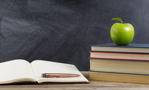 Rustik student skrivbordet med gröna äpple och studie material — Stockfoto