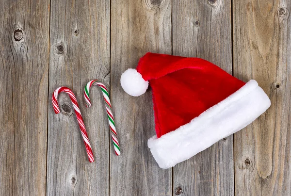 Fiesta tradicional Santa Claus gorra y bastones de caramelo en rústico wo — Foto de Stock