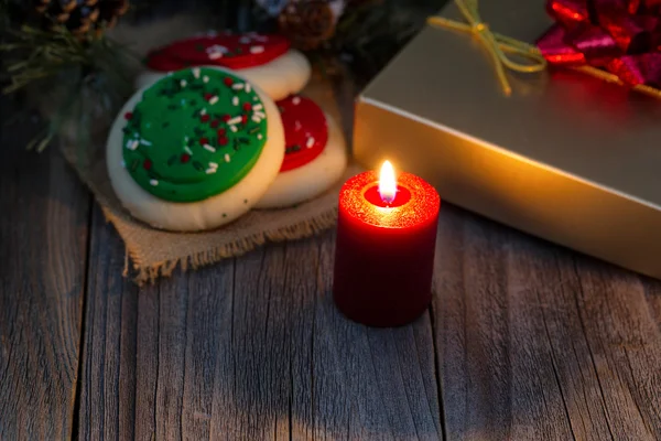 Leuchtend rote Kerze mit Geschenkkarton und Plätzchen auf rustikalem Holz — Stockfoto