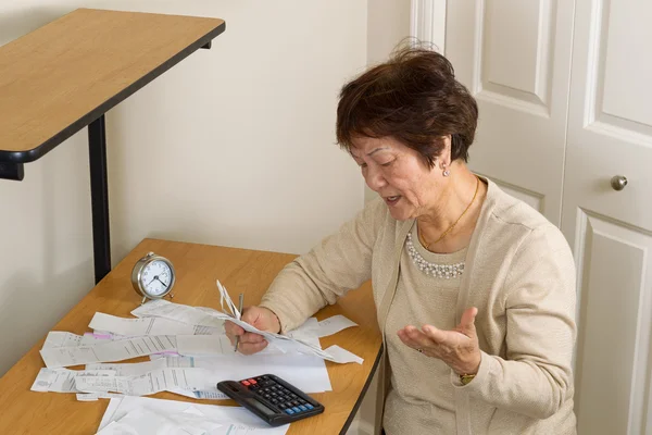 Oudere vrouw gefrustreerd door al haar financiële rekeningen — Stockfoto