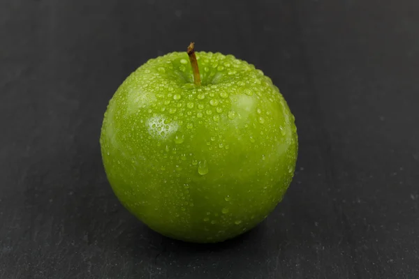 Maçã inteira verde fresca em fundo de ardósia preta — Fotografia de Stock