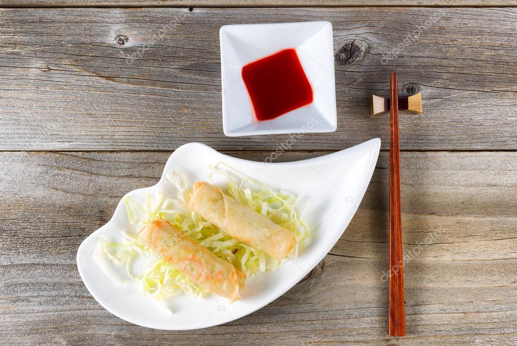 Fried Chinese spring rolls and sweet dipping sauce in white bowl