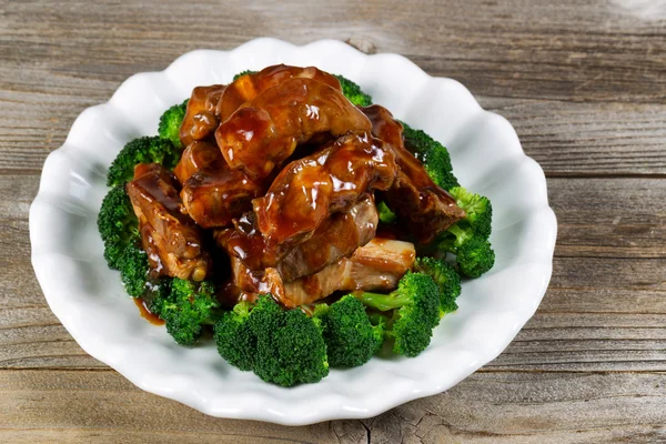 Super saucy barbecued ribs with vegetables on white plate — Stock Photo, Image