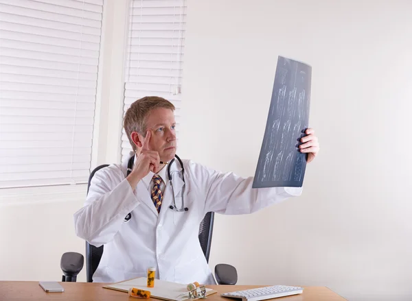 Dottore in pensiero, mentre guardando oltre grafico a raggi X — Foto Stock