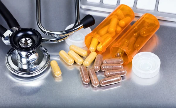 Capsules and medicine bottles plus medical equipment on stainles — Stock Photo, Image