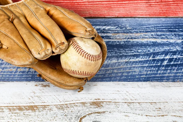 Old worn baseball mitt and ball on faded boards painted in Ameri — Stock Photo, Image