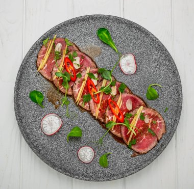 Sarımsaklı sığır eti, soya sosu, acı biber ve siyah tabakta zeytinyağı.