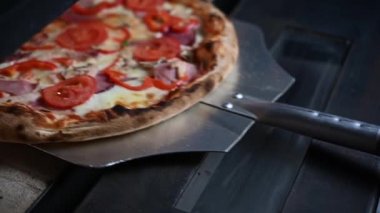 Şef pizzayı fırından çıkarır.