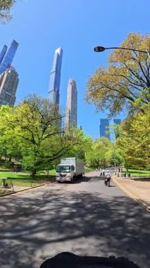 New York, ABD, 1 Ağustos 2025: Central Park yürüyüş yolu ve gökdelenler. Güneşli bir günde arka planda gökdelenlerle Central Park 'ta yürüyüş yolu.