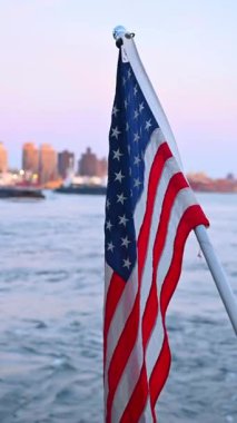 New York rıhtımında Amerikan bayrağı var. Arka planda New York 'un olduğu bir teknede Amerikan bayrağının yakın çekimi.
