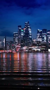 Hudson Yards gökdelenleri gece aydınlandı. Modern Hudson Yards gökdelenleri gece parlıyor, New York 'taki Hudson Nehri' ni yansıtıyor..