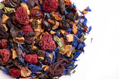 Renkli bitki çayı, kurutulmuş böğürtlenlerle harmanlanmış. Renkli bitkisel çayları kurutulmuş böğürtlenlerle, yapraklarla ve beyaz arka planda otlarla harmanlayın..