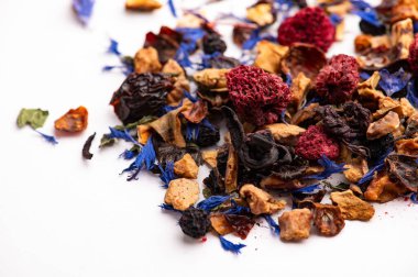 Kurutulmuş böğürtlen ve çiçeklerle karışık meyve çayı. Beyaz arka planda kurumuş ahududu, çiçek ve otlarla dağınık yapraklı meyve çayı..