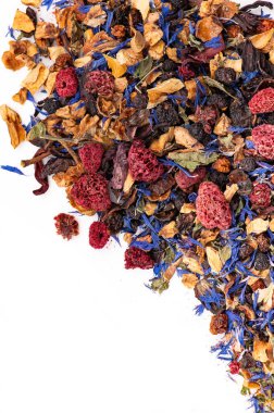 Kurutulmuş ahududu ve taç yapraklı bitki çayı karışımı. Kurumuş ahududu, çiçek yaprakları ve beyaz yüzeyde meyve parçaları ile bitki çayı karışımını kapat..