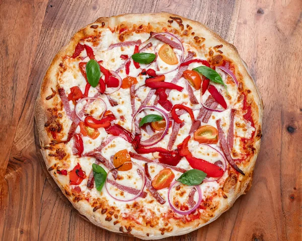 Fesleğen, mozarella, domates ve soğanlı ev yapımı pizza. Mozarella, kırmızı soğan, fesleğen yaprağı ve ahşap masada servis edilen kavrulmuş biberli ev yapımı lezzetli pizza..