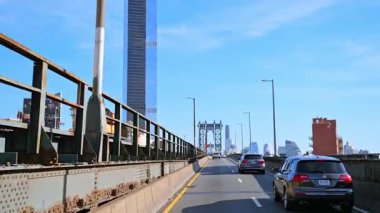 New York, ABD, 9 Ağustos 2025: Manhattan Köprüsü 'nü ufuk çizgisi manzaralı geçmek. Manhattan Köprüsü 'nü geçerken gökdelenler ve mavi gökyüzü.