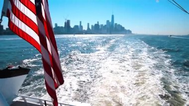 Manhattan Manzaralı Feribotta Amerikan Bayrağı. Bir feribotun arkasından sallanan Amerikan bayrağı. Manhattan silueti parlak gün ışığında..