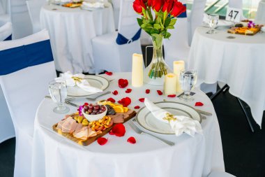 Güllü romantik bir masa. Güller ve mumlarla dolu romantik beyaz masa kutlamaya hazırlanıyor..