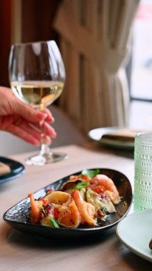 Beyaz şaraplı deniz ürünleri tabağı. Sıcak bir restoranda beyaz şarapla servis edilen lezzetli deniz ürünleri.