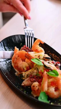 El ele tutuşan beyaz şarap kadehi. Sıcak restoranda deniz ürünleri tabağının üzerine beyaz şarap kadehi tutarken yakın plan..