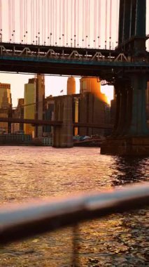 New York köprüleri arasındaki güneş ışığı. Doğu Nehri köprüleri arasında altın ışık yanıyor ve Manhattan kuleleri boyunca parlıyor..