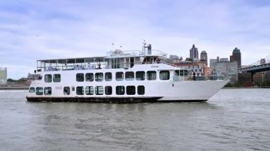 New York, ABD, 8 Kasım 2025: East River 'da beyaz yolcu gemisi. Yolcu gemisi Manhattan limanını geçiyor. Köprü kemerleri yükseliyor.