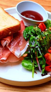 Jambonlu taze yeşillikler. Jambonlu tostun yanında domatesli taze yapraklı sebzeler..