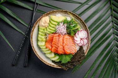 Avokado ve taze turplu somon balığı kasesi. Çekici bir somon balığı kasesi parlak somon, avokado, salatalık, turp ve deniz yosunu dilimlerini içerir..