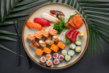 Büyük Suşi ve Sashimi Tabağı ile Edamame ve Crab. Kapsamlı bir tabakta suşi, sashimi ve yengeç ve edamame içeren maki dürümleri ve etrafındaki deniz yosunları yer alıyor..