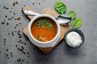 Maydanoz ve ekşi kremayla süslenmiş zengin et çorbası. Beyaz bir kase zengin, doyurucu et çorbası maydanozla süslenir, ekşi krema ve yansıtıcı bir kaşıkla servis edilir..