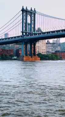 Manhattan Köprüsü Üssü Doğu Nehri üzerinde. Doğu Nehri 'nin dalgalı suyundan yükselen Manhattan Köprüsü' nün karanlık üssünü görüntüleyen dikey görüntü..