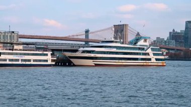 New York, ABD, 5 Aralık 2025, Brooklyn Köprüsü 'ne yanaştı. İki büyük beyaz yolcu gemisi kıyıya yakın nehre yanaştı, asma köprü ve ufuk çizgisi uzaklıktan görülebiliyor..