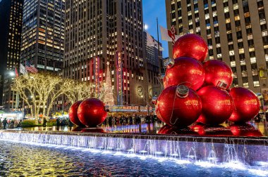 New York, ABD, 9 Aralık 2025: Aydınlatılmış Midtown Çeşmesi 'ndeki kırmızı süsler. Geceleyin dekore edilmiş şehir ağaçlarının yanında sahnelenen mevsimlik eğlence