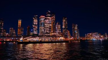 New York, ABD, 24 Aralık 2025, Hudson River Skyline with Night Boat. Yolcu gemisi Hudson Nehri boyunca gece aydınlatılmış Manhattan silueti ile yol alarak sinematik şehir manzarası yaratıyor..