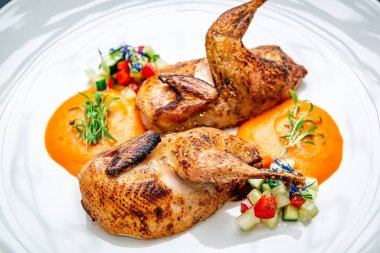 Izgara tavuk, sebzeli ve soslu beyaz tabakta servis edilir. İki parça kızarmış tavuk ve yanında renkli sebzeler ve sos olan bir tabağa konmuş kanatlar..