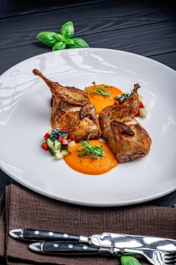 Beyaz tabakta servis edilen nefis bıldırcın tabağı ve yanında renkli salata. Bıldırcın, portakal sosu ve beyaz tabakta salata ile servis edilir. Taze bitkiler yemeğin yanına konur..