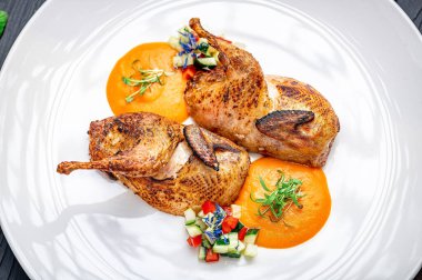 Restoranda beyaz bir tabakta soslu ve sebzeli tavuk. Sos ve doğranmış sebzelerle birlikte beyaz bir tabağa konmuş pişmiş tavuk. Restoranda servis edilen yemek..