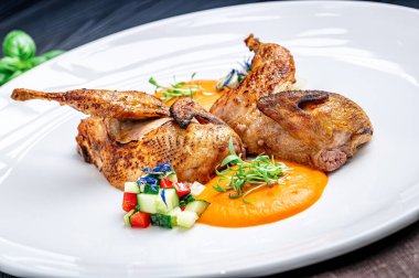 Sebze salatası ve sosla servis edilen ızgara tavuk. İki parça ızgara tavuk, yanında sebze salatası ve sos olan beyaz bir tabakta oturur..