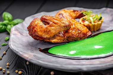 Şef yeşil sos ve sebze garnitürlü ızgara tavuk yemeği hazırlıyor. Şef yeşil soslu ızgara tavuk ve siyah tabakta taze sebze servis ediyor..