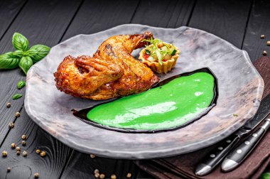 Yeşil soslu ızgara tavuk ve gri tabakta salata. İçinde yeşil soslu ızgara tavuk ve küçük bir salata var..