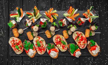 Delicious food spread with salads and bread on wooden table at gathering. Friends enjoy a spread of fresh salads, breads, and vegetables at a gathering on a wooden table.