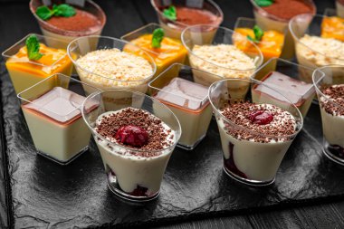 Akşamki toplantıda tatlılar karanlık bir masaya dizildi. Kara tahta üzerinde çeşitli tatlılar sergilenir. İnsanlar bu tatlı ikramların tadını çıkarabilir..