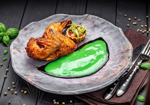 Yeşil soslu ızgara tavuk kanadı ve tabakta salata. Izgara tavuk kanadı yeşil sos ve tabakta küçük bir salatanın yanına yerleştirilir..