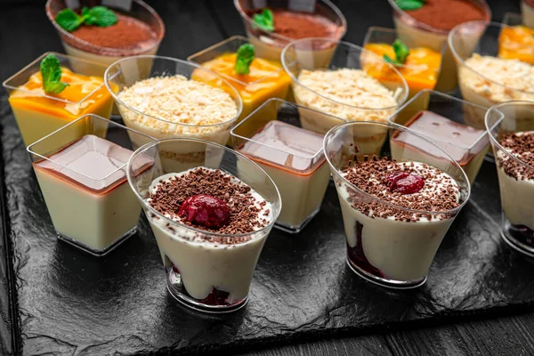 Akşamki toplantıda tatlılar karanlık bir masaya dizildi. Kara tahta üzerinde çeşitli tatlılar sergilenir. İnsanlar bu tatlı ikramların tadını çıkarabilir..