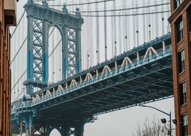 Manhattan Köprüsü bulutlu bir günde New York 'ta sokak seviyesinden görüldü. İnsanlar bulutlu bir havada New York 'ta kaldırımdan Manhattan Köprüsü' nü görüyorlar..