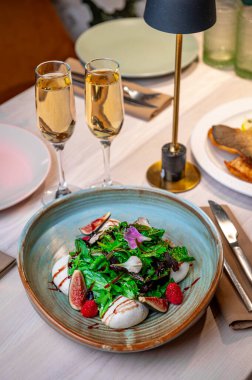 Lokantadaki yemek masasında taze salata, meyve ve içecek. İki bardak içki bir kase salatanın yanına otur. Restoran ortamında bir masada meyve olsun..