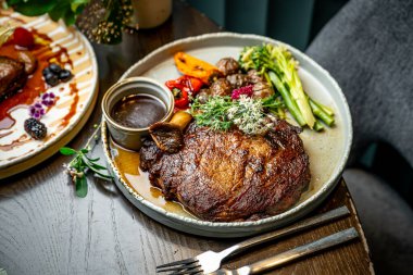 Şef yemek masasında sığır eti ve sebzelerle kaplanmış bir yemek hazırlar. Bir şef büyük bir parça sığır eti ve kızarmış sebze ve sosu akşam yemeğinde tabakta servis eder..